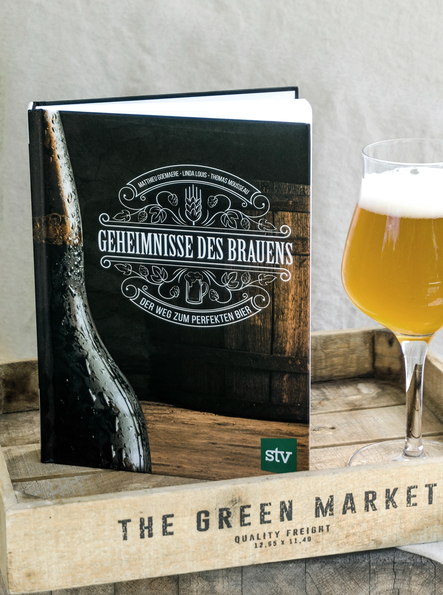 Geheimnisse des Brauens Buch mit Bierglas auf Holztablett