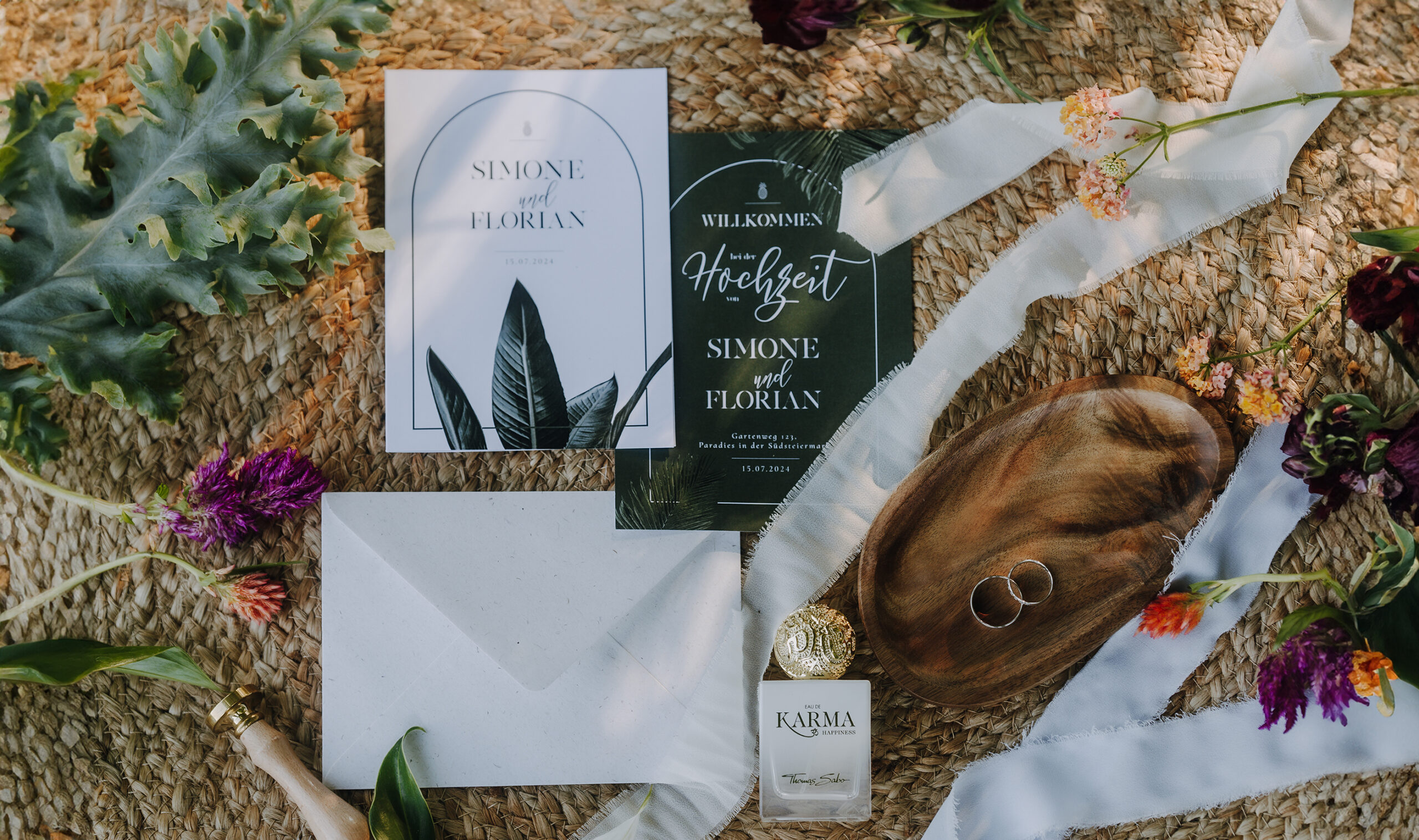 Hochzeitseinladungen und Dekoelemente mit Blumen und Blättern.