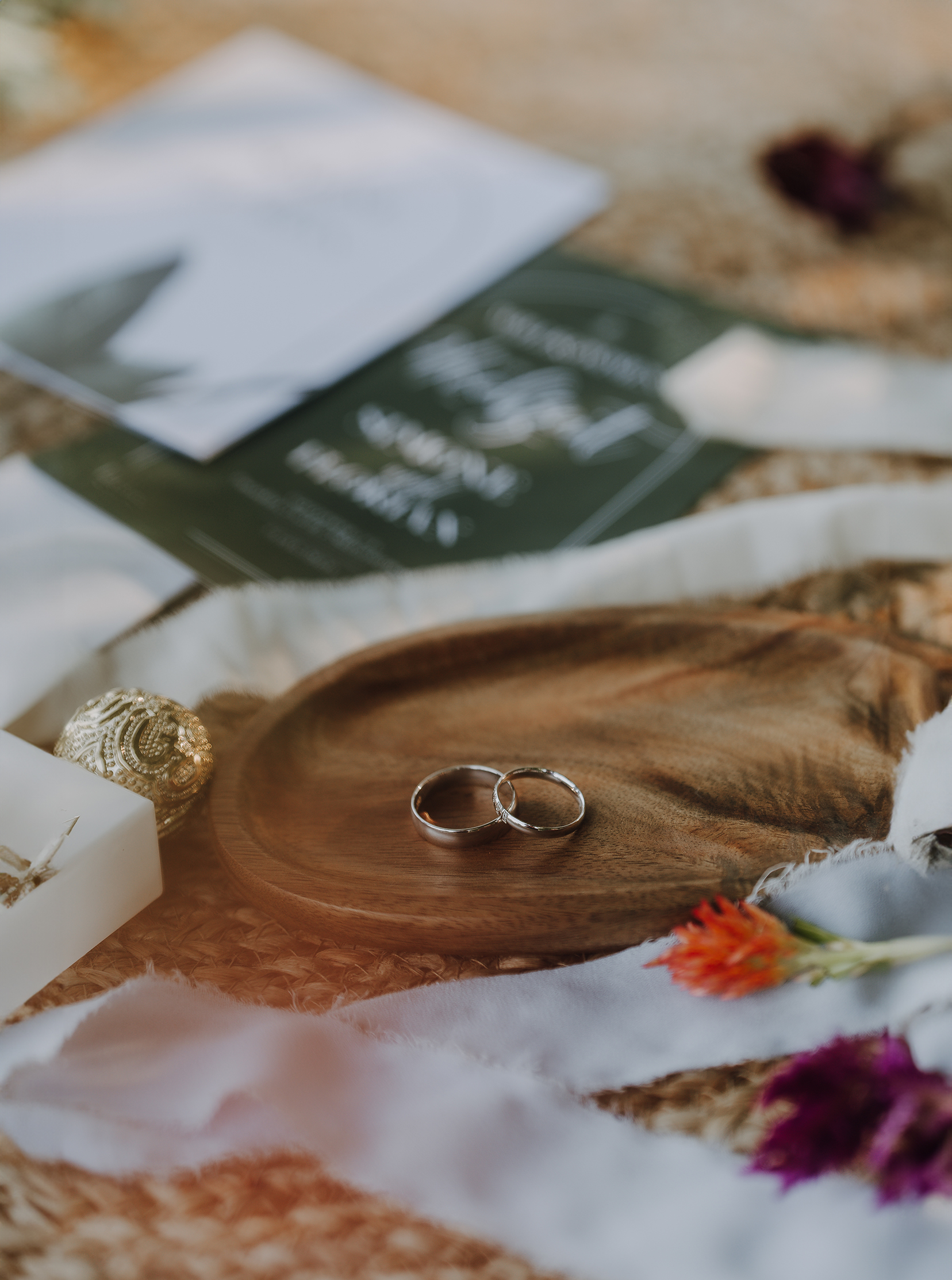 Eheringe auf einem Holztablett mit Hochzeitskarten und Blumen.