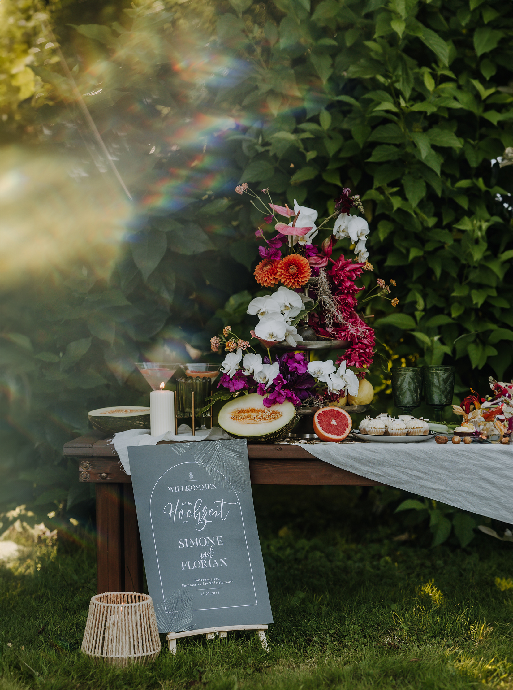 Willkommensschild bei einer Hochzeit mit Blumen und Kerzen.