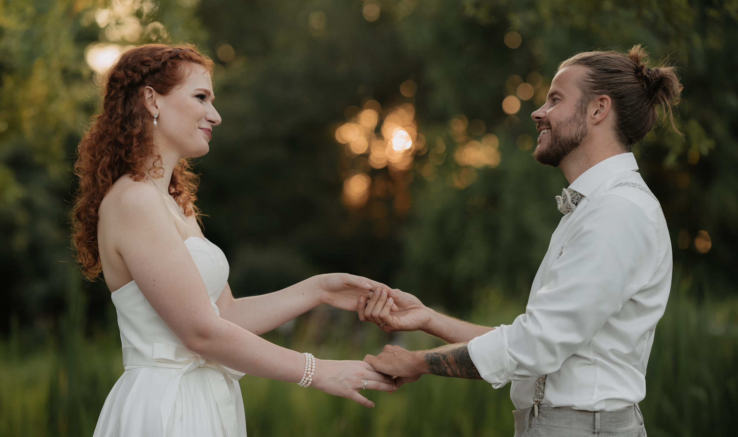 Brautpaar im Garten, das sich bei der Hochzeit die Hände hält.